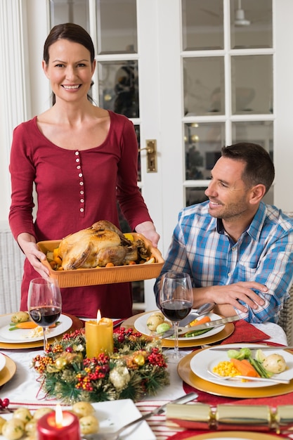 Couple smiling while woman holding roast turkey