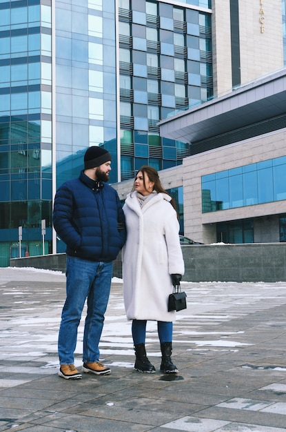 couple in snowy park. young man, woman. warm sweaters. People walking. Family winter holidays. Date