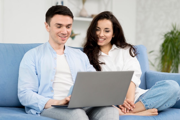 Couple on sofa at home with laptop