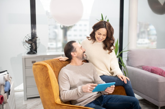 Couple spending their time in the furniture salon watching video