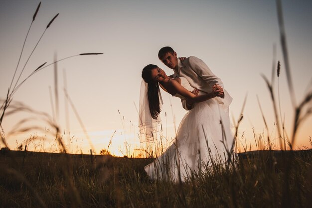 Photo couple standing on field against sky during sunset