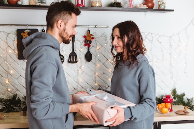 Couple standing kitchen open gifts presents garlands home cosy interior atmosphere New Year