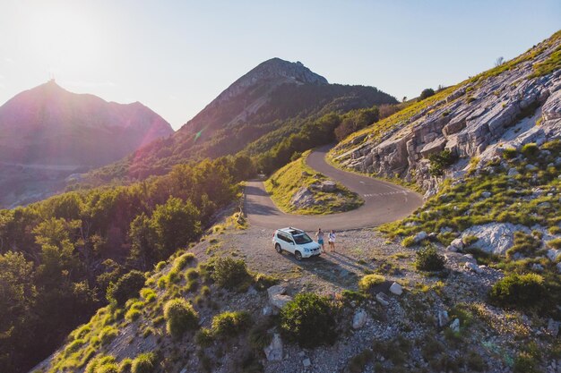 Couple standing near white suv car on the edge of the hill. aerial view. car travel