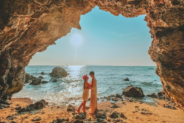 Couple standing on a rock at the cave entrance Look at the sea and beautiful views at sunset romantic atmosphere at Kho Larn Thailand