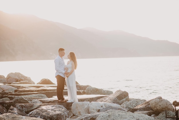 A couple standing on a rock in front of the sea