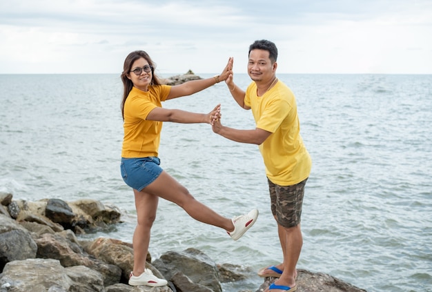 Couple standing on a rock near the sea