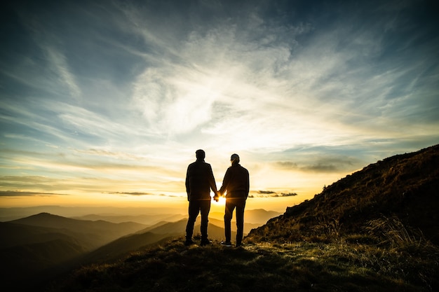 The couple standing on the rock with the picturesque sunrise