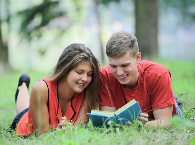 Couple of students lying on the grass in the Park and reading a book