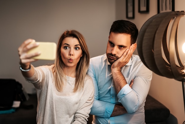 Couple taking funny selfie in their home.