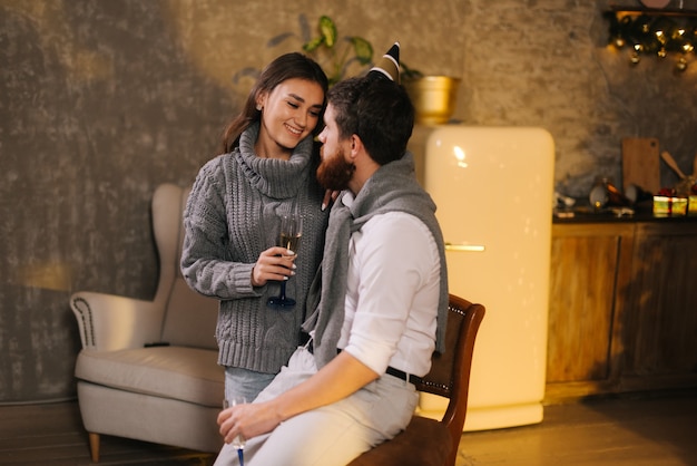 Couple talking on New Year Eve Lovers boyfriend and girlfriend communicate nicely in festively decorated room. Girl holds glass of champagne in hands.