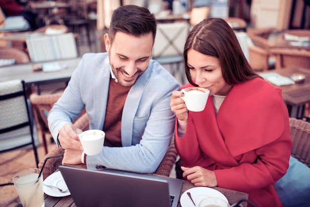 Couple talking and using laptop at cafe