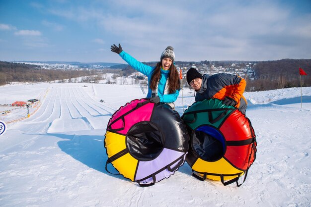 Couple at top of the hill ready for snow tubing winter activity slide from the top