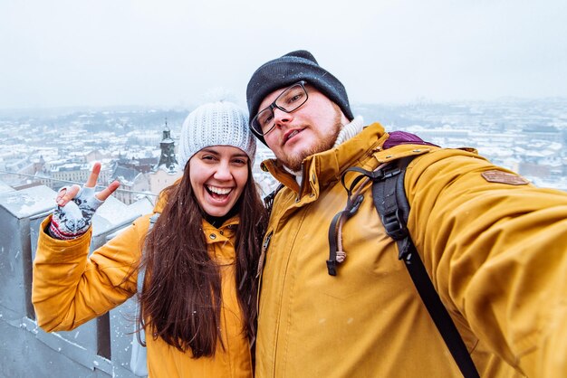 Couple tourists taking selfie with beautiful city view in winter time on background