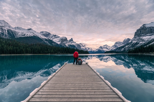 Couple traveler relaxing on wooden pier in Maligne lake at Spirit island, Jasper national park