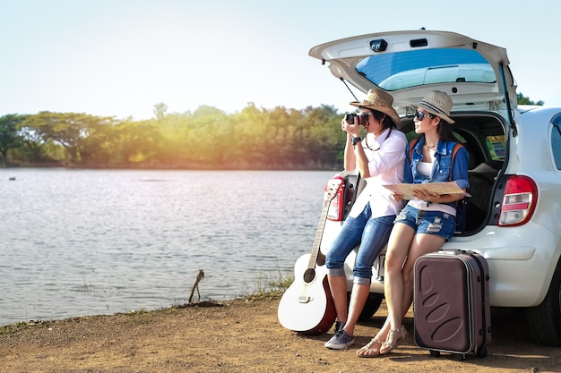 Couple traveler sitting on hatchback of car and enjoying for view of nature near the lake 