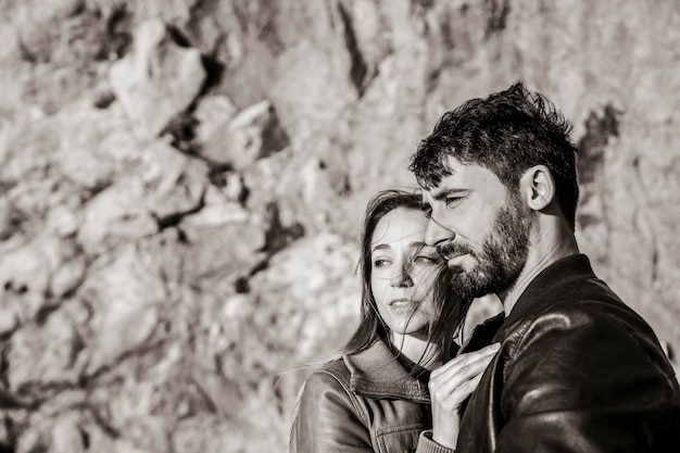 Couple of travelers looking far away at sunset against a rock background Boyfriend and girlfriend during a trip into the nature Black and white style