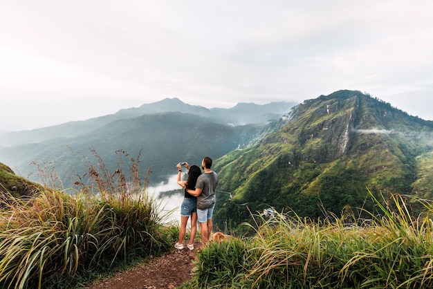 The couple travels the world. A couple in love travels to Sri Lanka. The couple travels to Asia. Man and woman meet the dawn in the mountains. Vacation in Asia. Happy couple in the mountains.