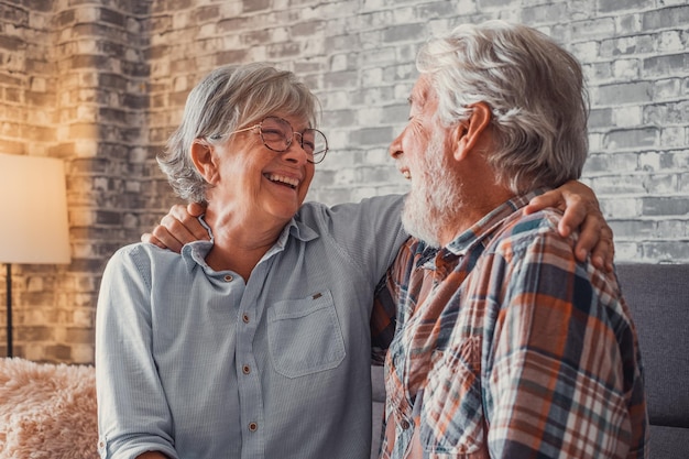 Couple of two old seniors having fun together and enjoying on the sofa at home Mature people talking and laughing hugged