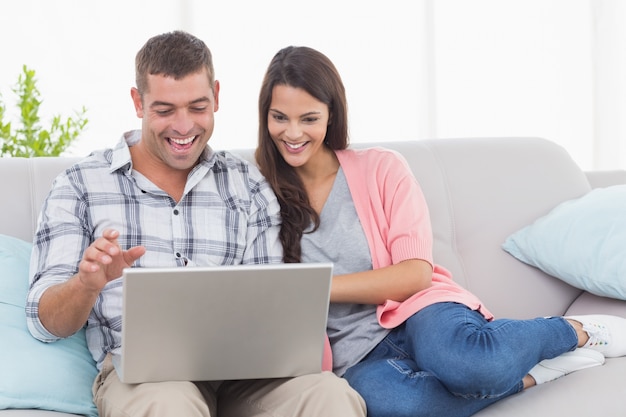 Couple using laptop for video conference on sofa