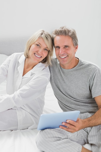 Couple using their tablet pc smiling at camera