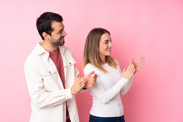 Couple in Valentine Day over isolated pink wall applauding after presentation in a conference