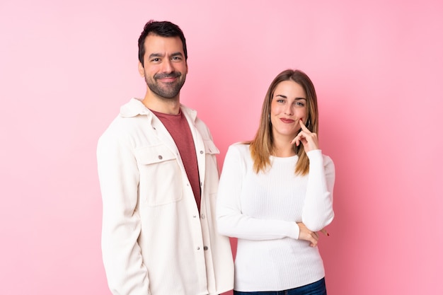 Couple in Valentine Day over isolated pink wall smiling with a sweet expression