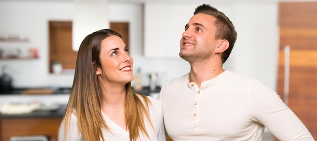 Couple in valentine day looking up while smiling in a house