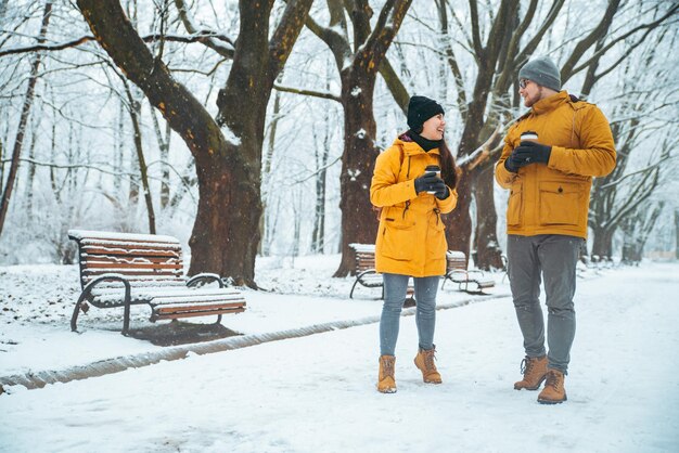 Couple walking by snowed city park talking socializing romantic date in winter time