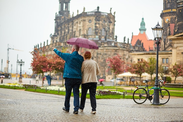 A couple walks around the city under one umbrella while it's raining