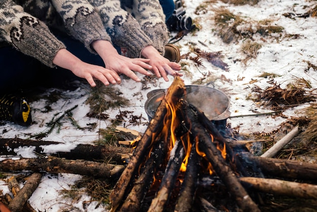 Couple warms their hands by the fire in winter