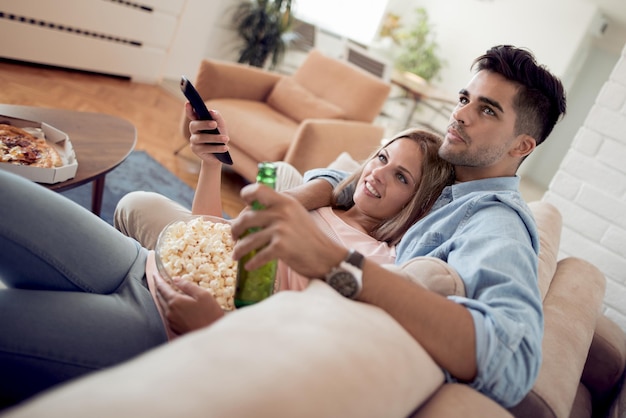 Couple watching TV and eating popcorn