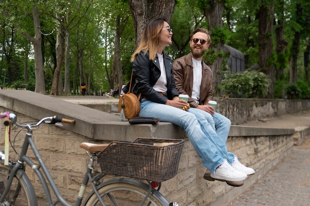 Photo couple wearing synthetic leather jackets having coffee together outdoors