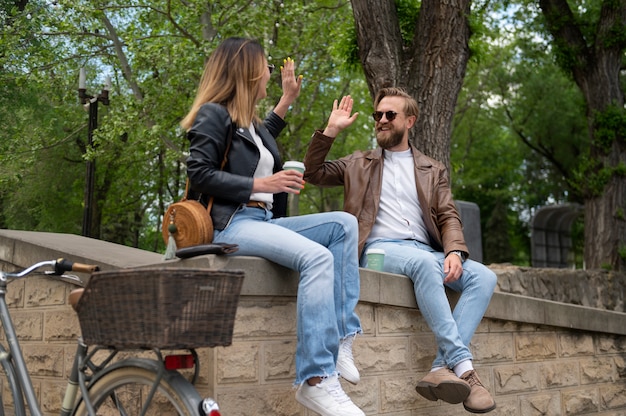 Couple wearing synthetic leather jackets having coffee together outdoors