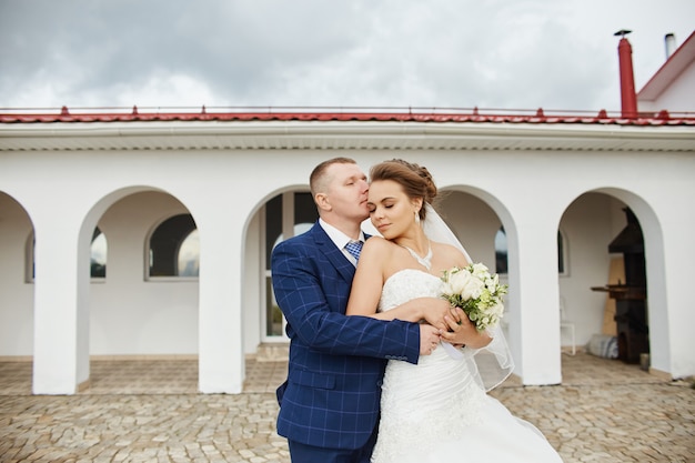 Couple wed embrace and kiss next houses near water