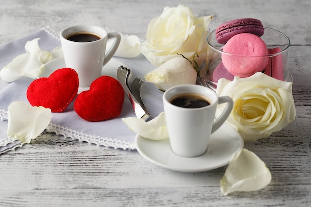 Couple white cups with decoration by red hearts on wooden table. Valentine's day celebration concep