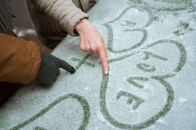 Couple in winter writing love with heart in the snow