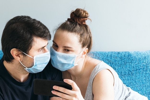 Couple with blue medical face masks looking at a smartphone