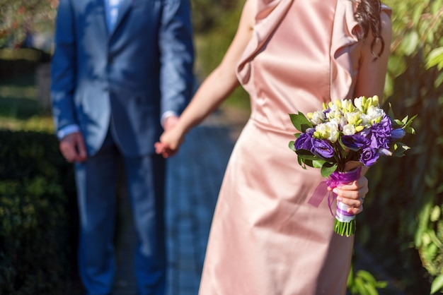 couple with bouquet outdoors holding hands