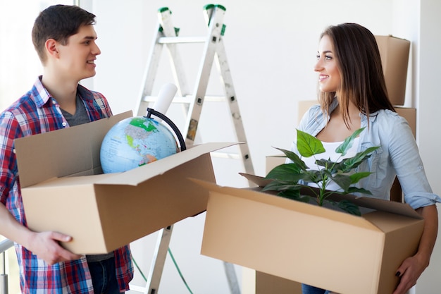 A couple with boxes moves to a new house. Property For Sale.