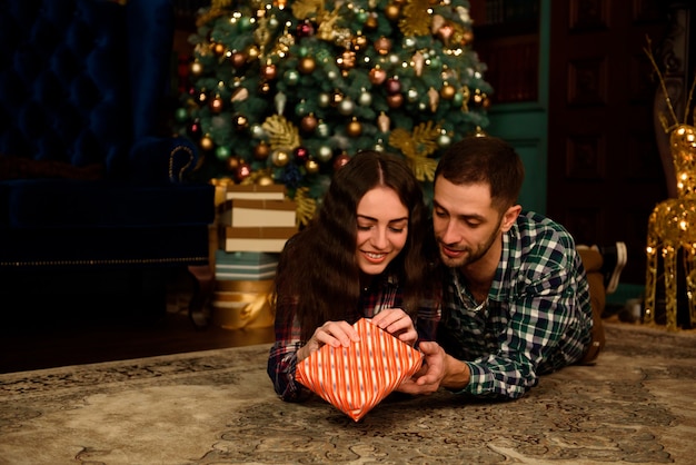 Couple with Christmas present at home on the flour