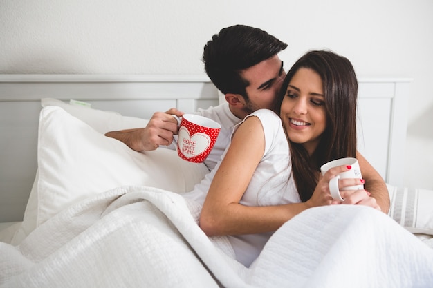 Couple with coffee cups in bed