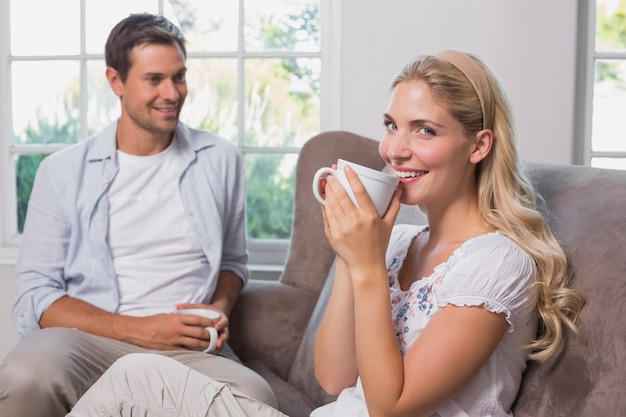 Couple with coffee cups sitting in living room