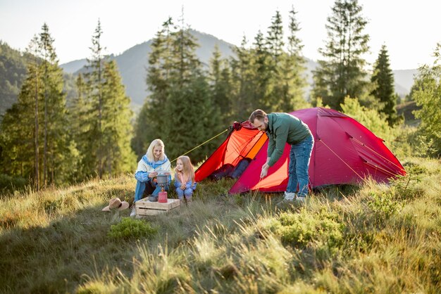 Couple with little girl have picnic at campsite in the mountains