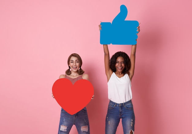 Couple woman cheerful smile showing red heart with like icon symbol on pink studio background