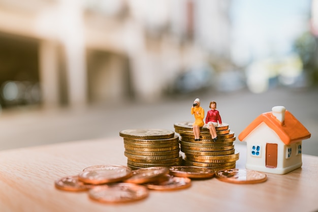 couple woman sitting on stack coins and mini house 