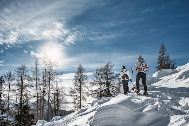 Couple of women friends on snow trip with snowshoeing