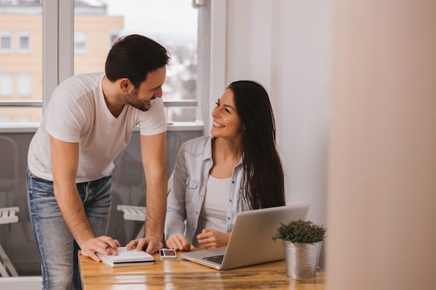 Couple working together at home, looking at each other and smiling