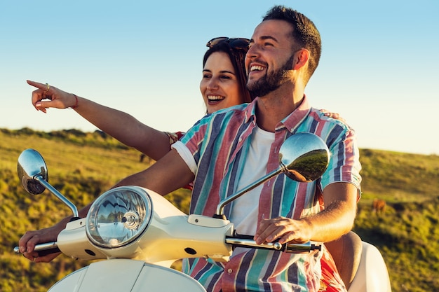 Couple of young friends having fun and smiling on a motorcycle