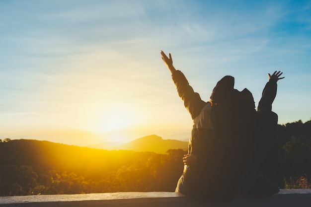 Couple young girl with enjoying and looking sunset on peak of foggy mountain.