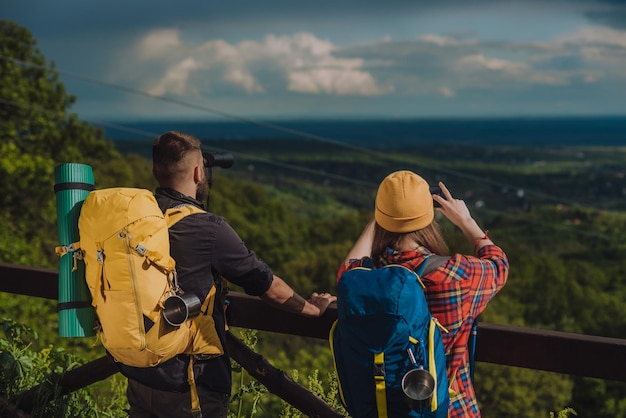 Couple of young hikers taking photo with a smartphone and looking into nature